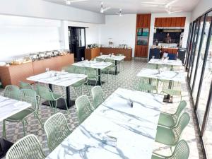 a dining room with white tables and green chairs at River Bay Athirappilly in Athirappilly