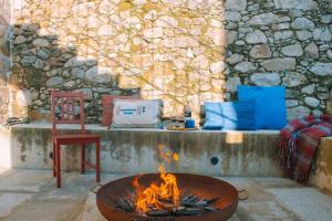 a fire pit with a chair next to a stone wall at Just Like Home - Casa da Tuca in Moledo
