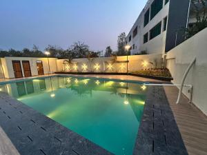 a swimming pool in front of a building at night at Hotel Sai Inn at Statue of Unity in Rājpīpla