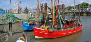 a red boat is docked in the water at Ferienhaus Strandallee 10 in Burhave