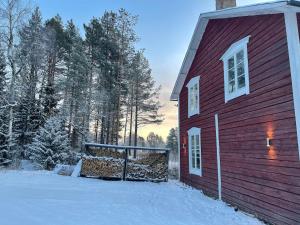 a red barn with snow on the ground next to it at Villa Björksele in Björksele