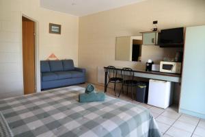 a room with a bed and a couch and a kitchen at Curtain Fig Motel in Yungaburra