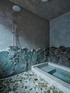 a bathroom with a bath tub in a room with rocks at shinso hakone in Hakone