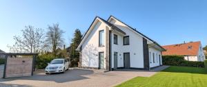 a white car parked in front of a white house at Ferienhaus Strandallee 10a in Burhave