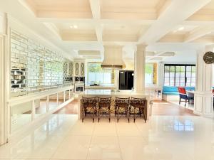 a kitchen with white walls and a large island with bar stools at Pool Villa Pattaya 5BD - Exquisite Pool Villa G in Nong Prue