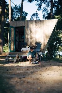 a man sitting in front of a tiny house at Tiny Houses Klein Ahoi Camp Canow in Wustrow +2 photos