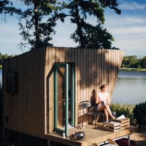 a woman sitting on the deck of a tiny house at Tiny Houses Klein Ahoi Camp Canow in Wustrow