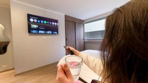a woman holding a cell phone and a glass of water at La Carolina Suite Moderna - Excelente Ubicación in Quito