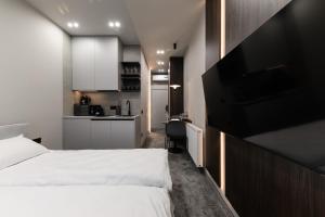 a bedroom with a white bed and a kitchen at EVURI Apartments BUDAPEST 2 in Uzhhorod