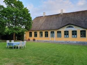 a yellow building with a table and chairs in front of it at Inseldomizil Brummers Gaard in Haderslev