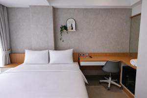 a bedroom with a bed and a desk and a tv at The Orchid by FLAT06 in Jakarta