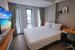 a hotel room with a large bed and a tv at The Orchid by FLAT06 in Jakarta