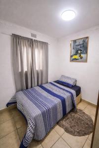 a small bedroom with a bed and a window at PrimeStay One 2 Bedroom Apartment in Johannesburg +6 photos