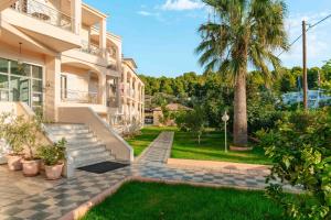 a house with a palm tree and a sidewalk at Hotel Panorama in Koukounaries