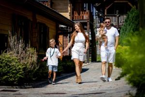Eine Familie geht auf einem Bürgersteig entlang, während sie eine Straße entlanggeht in der Unterkunft Western Camp Resort in Zator