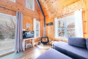 a living room with a couch and a tv and windows at Spa Outdoor & Adventure - LEnigmasud in Saint-Philémon