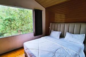 a bed in a room with a large window at Spekta Merbabu powered by Cocotel in Jlarem
