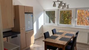 a kitchen with a wooden table with chairs and a kitchen with two windows at Ferienwohnung Achelpöhler in Hagen im Bremischen