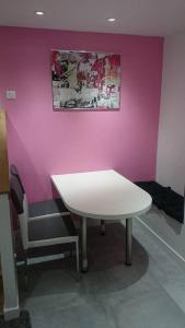 uma mesa e uma cadeira num quarto com uma parede rosa em The Pearl of Marais em Paris