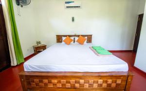 a bedroom with a bed with white sheets and orange pillows at Kataliya Villa in Ahungalla +2 photos