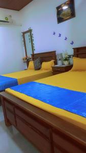 two beds in a room with yellow and blue sheets at Mandara Holiday Home in Anuradhapura