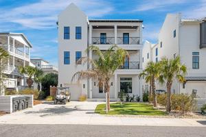 a white building with palm trees in front of it at Oz by The Sea in Inlet Beach