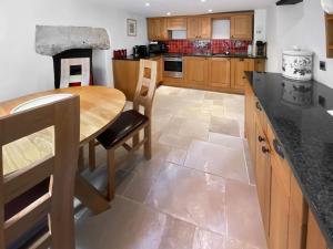 a kitchen with a wooden table and a counter top at Folly Cottage in Avening