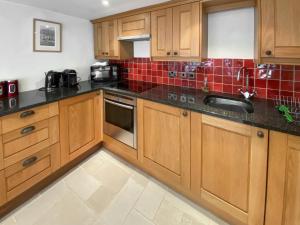 a kitchen with wooden cabinets and red tiles at Folly Cottage in Avening