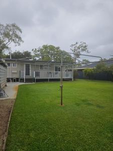 a house with a yard with a pole in the grass at Bongaree Beach Shack - close to the bridge! in Bongaree
