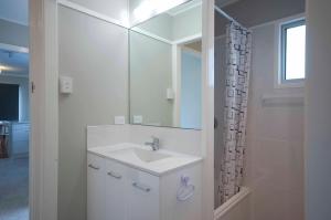 a white bathroom with a sink and a mirror at Bongaree Beach Shack - close to the bridge! in Bongaree +35 photos