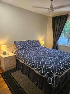 a bedroom with a bed with a blue comforter and a window at Bongaree Beach Shack - close to the bridge! in Bongaree