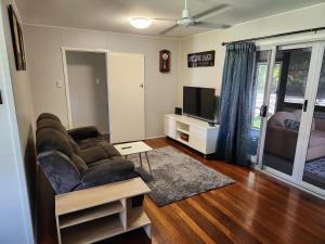 a living room with a couch and a television at Bongaree Beach Shack - close to the bridge! in Bongaree