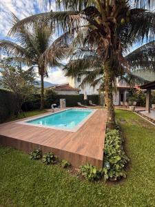 a swimming pool with a palm tree next to it at Casalapraia in Caraguatatuba