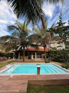 a swimming pool in front of a house with palm trees at Casalapraia in Caraguatatuba