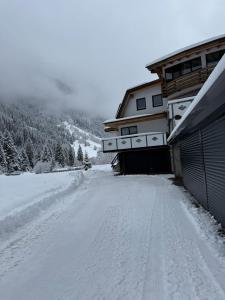a snow covered road in front of a house at AusZeit in Gschnitz