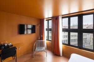 a room with a large window with a chair and a desk at People Lyon Hotel in Lyon