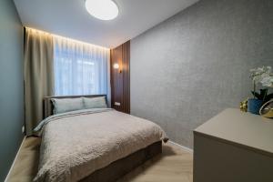 a small bedroom with a bed and a window at Sandal Apartments in Šiauliai