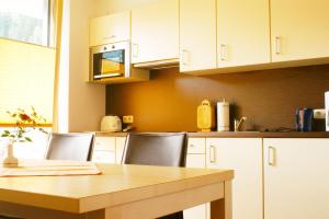 a kitchen with a wooden table and white cabinets at Apart Flürs in Flirsch