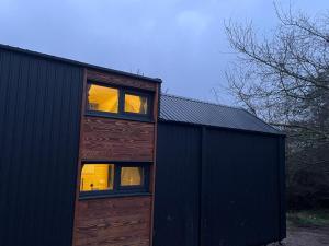 a wooden cabin with windows on the side of a building at Badgers Hollow by Tiny Away in Whitchurch