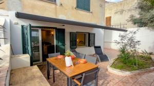 a patio with a wooden table in front of a building at Casa CarMa - Relax & Comfort a Cala Gonone in Cala Gonone