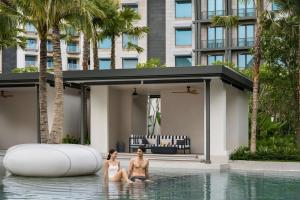 two women sitting in the water in a swimming pool at The Laurus, a Luxury Collection Resort, Singapore in Singapore