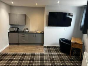 a room with a kitchen with a television on the wall at Crown Hotel & Bar in Inverness