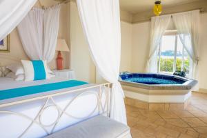 a bedroom with a bed and a tub at Ile Des Deux Cocos in Blue Bay