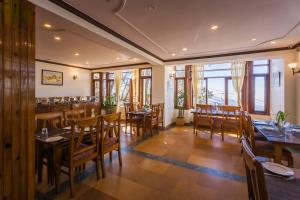 a restaurant with wooden tables and chairs and windows at Tripli Hotels Le Royale, Shimla in Shimla