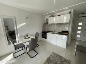 a kitchen with white cabinets and a table and chairs at Studio apartman Sunset cove in Stinica