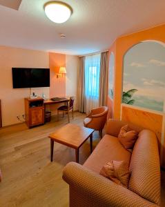 a living room with a couch and a desk in a hotel room at Hotel Restaurant Felix in Bensheim