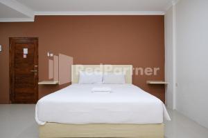 a bedroom with a white bed and a brown wall at Hotel Andono near YIA Mitra RedDoorz in Yogyakarta