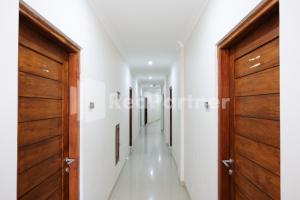 a hallway with wooden doors and white walls at Hotel Andono near YIA Mitra RedDoorz in Yogyakarta +50 photos