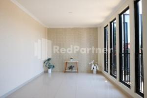 a hallway with large windows and white tiles at Hotel Andono near YIA Mitra RedDoorz in Yogyakarta
