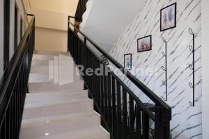 a staircase with a white brick wall with pictures on it at Hotel Andono near YIA Mitra RedDoorz in Yogyakarta